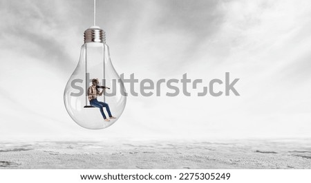 Man plays on violin sitting on light bulb