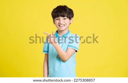 portrait of an asian boy posing on a yellow background Royalty-Free Stock Photo #2275308857