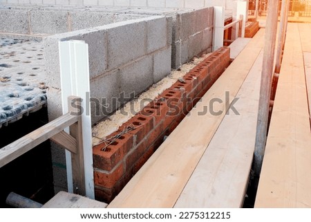 Insulating walls of new build houses by placing rock wool inside wall cavities as part of the energy-saving measures. House insulated with mineral wool to reduce the energy bill Royalty-Free Stock Photo #2275312215