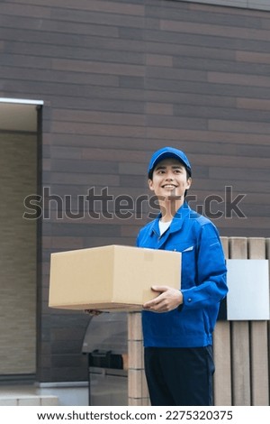 Asian male worker holding a cardboard. Delivery staff. Royalty-Free Stock Photo #2275320375
