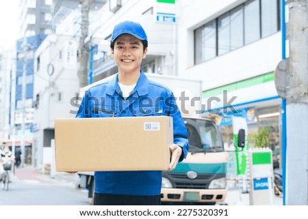 Asian male worker holding a cardboard. Delivery staff.