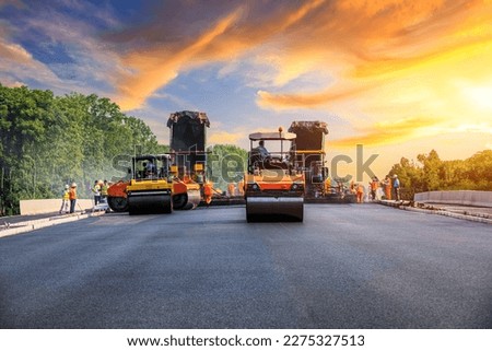 Construction site is laying new asphalt pavement, road construction workers and road construction machinery scene. Highway construction site scene. Royalty-Free Stock Photo #2275327513