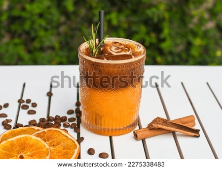 Bumble coffee on white wooden table with coffee beans against green leaves with copy space