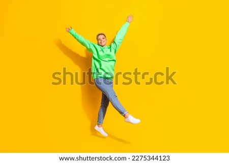 Full size portrait of cheerful overjoyed girl jumping raise hands empty space isolated on yellow color background