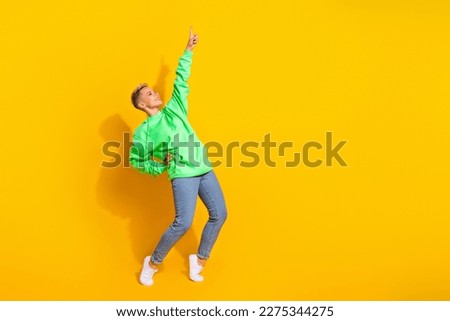 Full body length photo of hipster dancer lady wearing modern trendy outfit finger point up look empty space club isolated on yellow color background