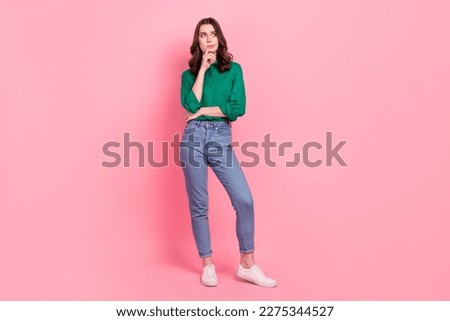 Full size photo of ponder pensive thoughtful girl dressed jeans green shirt look empty space finger on chin isolated on pink background