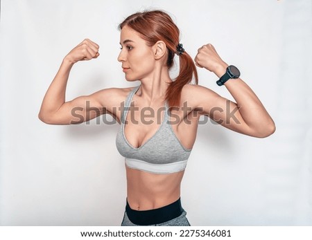 Biceps. Strong female arm muscles. Sporty woman posing on white background. Fitness classes
