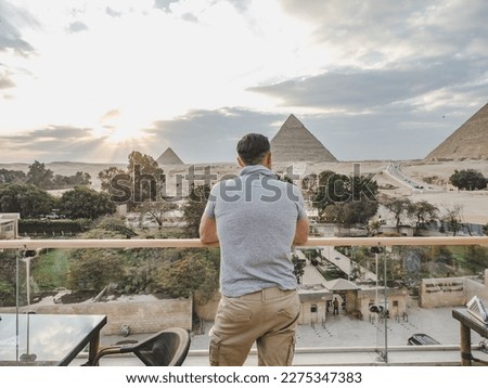 Stylish man against the background of the Giza pyramid complex. Clear, sunny day, blue sky. Vacation and travel concept
