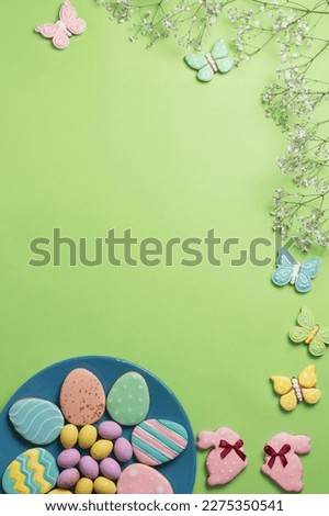 Easter banner on a green background. Homemade gingerbread cookies on a blue plate, Easter eggs and cookies in the shape of a rabbit and a butterfly. Easter concept.