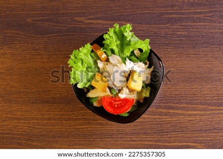 Caesar salad in black plate on the table top view