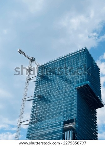 Photo of a building under construction with cloudy sky as background. Copy space