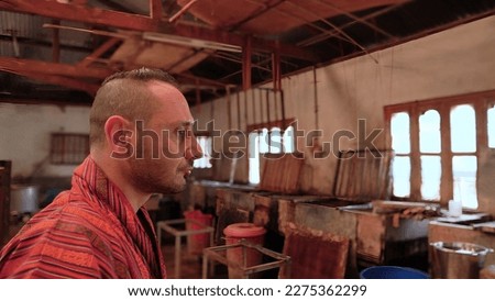 Tourist man with traditional Bhutanese clothes visit paper production factory in Thimphu, Bhutan