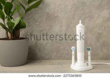 Electric toothbrush with green flower on grey background. Top view
