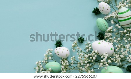 Easter concept. Top view photo of colorful easter eggs with white Gypsophila  on isolated pastel green background with copy space