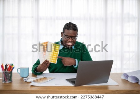 Happy African American Male Designer Showing Color Palette To Laptop Computer Having Video Call With Client Sitting At Desk In Modern Office. Design And Colors Trends Concept