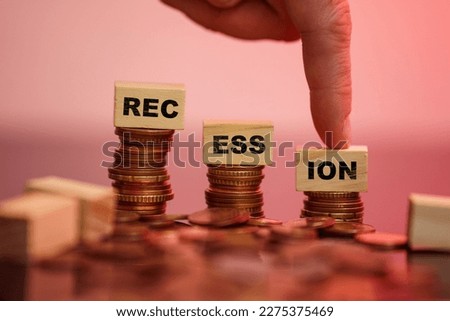 Recession of the economy concept symbol. Finger point on wooden cube. Recession word cubes on coins going down. . High quality photo
