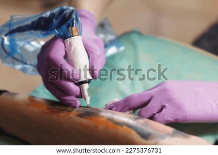 Ink artist making a new tattoo in close up Royalty-Free Stock Photo #2275376731