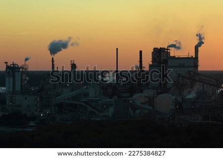 Aerial view of large factory with smokestack from production process polluting atmosphere at plant manufacturing yard. Industrial site at sunset Royalty-Free Stock Photo #2275384827