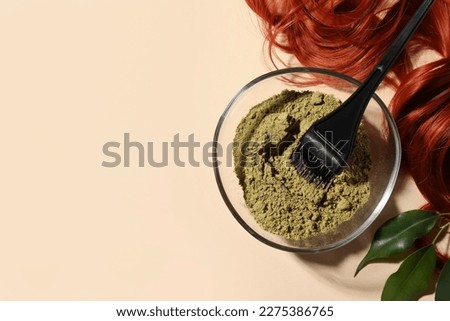 Bowl of henna powder, brush, green leaves and red strand on beige background, flat lay with space for text. Natural hair coloring