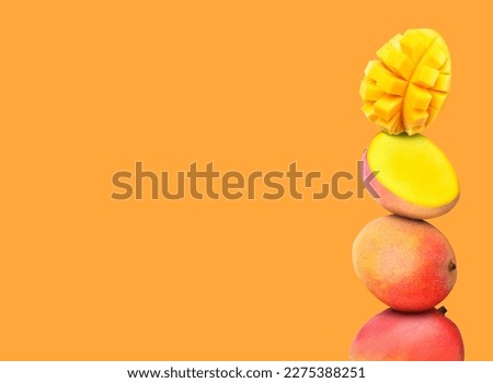 Stacked fresh mango fruits on orange background, space for text