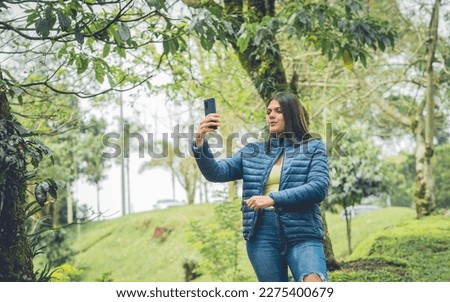 Young woman outdoors, while playing and interacting with her cell phone
