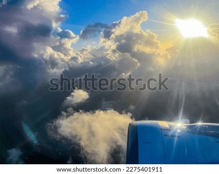 A feeling of travel, escape and freedom provoked by this image of a plane engine above a cloudy sky with the sun against the light seen through a window