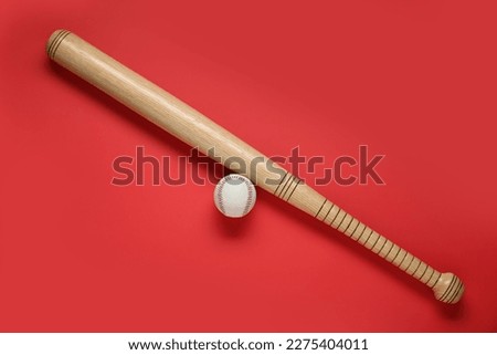 Wooden baseball bat and ball on red background, flat lay. Sports equipment