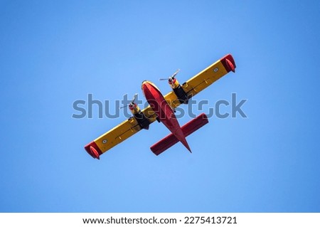 Canadair Firefight Aircraft, Scooper flying on blue sky background, under view. Yellow red color seaplane flight for rescue and transport.