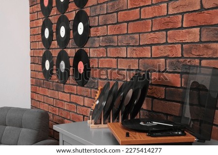 Vinyl records on brick wall and wooden player in living room