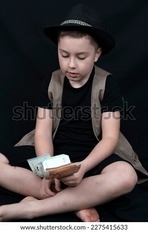 Little boy business boy with bundle of money count euro cash on the black background.
