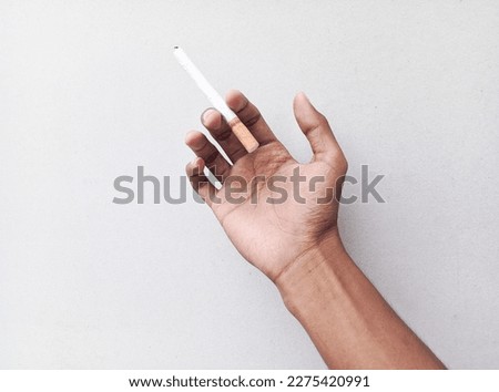 Hand holding a cigarette on a white background.