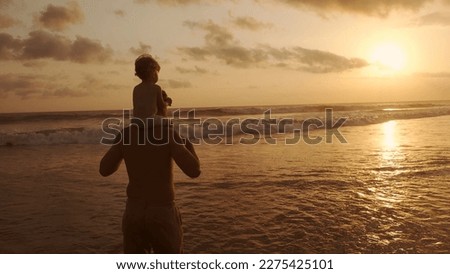 Family idyll - Father playing with his little son on beach during sunset, carrying him on his shoulders, enjoying their vacation together - recreational pursuit, dream concept 