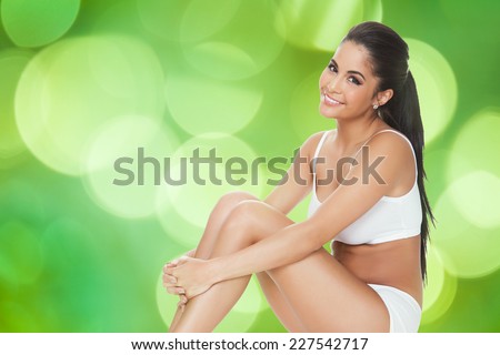 Portrait of happy woman in innerwear sitting against green background