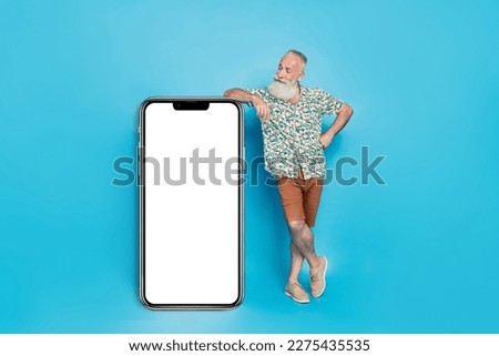 Full body photo of positive aged man look big empty space telephone screen isolated on blue color background