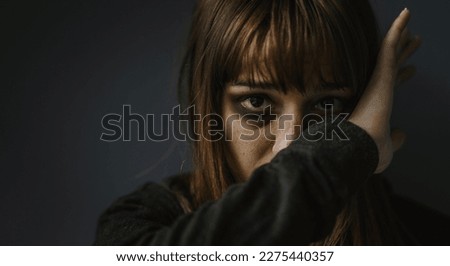 Portrait picture of beaten woman standing in front of a dark wall - Stop violence against women concept Royalty-Free Stock Photo #2275440357