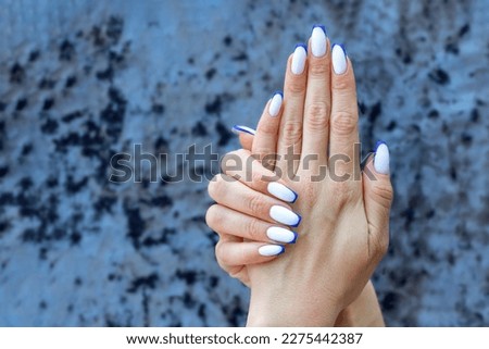Color French manicure white ombre on the nails with blue stripes on the tips. Royalty-Free Stock Photo #2275442387
