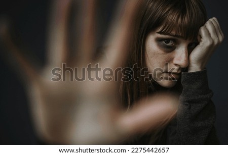 Portrait picture of beaten woman standing in front of a dark wall - Stop violence against women concept Royalty-Free Stock Photo #2275442657