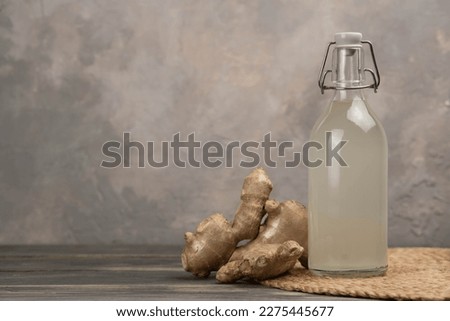 Bottle with homemade ginger ale, lemon and gingerroot on gray background. Front view. Royalty-Free Stock Photo #2275445677