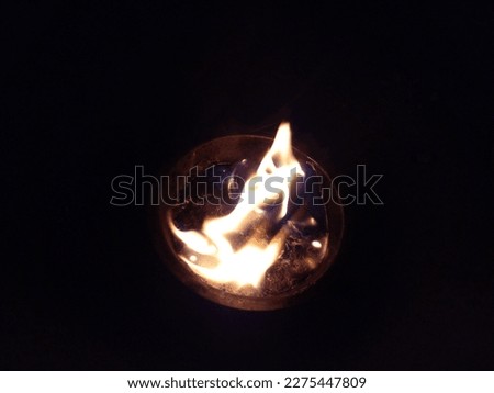 Photo of a flame burning plastic waste in a small aluminum bowl