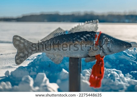 Lake direction sign metal fish shape, winter time, lake with snow and ice.