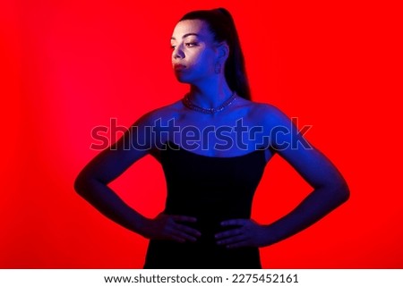 Fashionable silhouette of a young woman on a red background with a necklace around her neck .