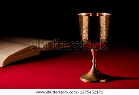 christian chalice with open bible on red background Royalty-Free Stock Photo #2275452171