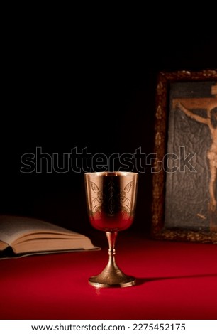 christian chalice on altar open bible and crucified jesus christ picture with strong red background
