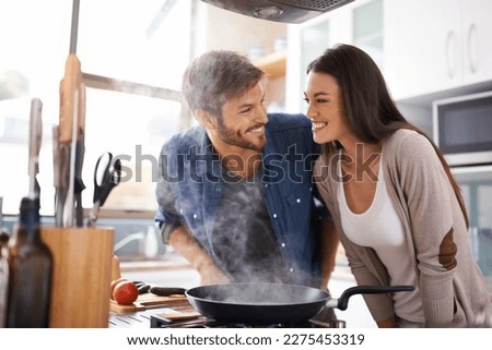 Simmer down you two. A young couple making dinner together at home. Royalty-Free Stock Photo #2275453319