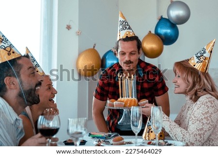 Excited Latin Man with mustache ready to blow out Birthday candles with friends