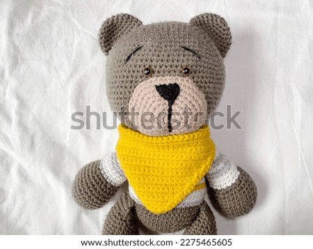 A brown bear in a yellow bib on a white background. Cute knitted bear. Amigurumi teddy bear. boneka rajut beruang.