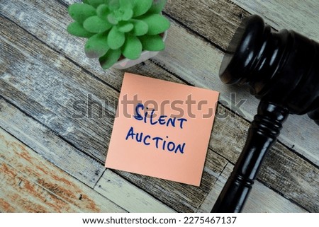 Concept of Silent Auction write on sticky notes with Gavel isolated on Wooden Table. Royalty-Free Stock Photo #2275467137
