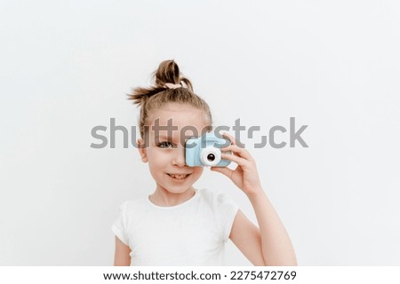 The gadgets for kids. Cute small todler girl with toy photo camera. White background.