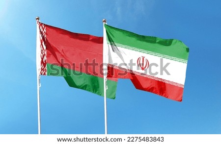 Iran flag and Belarus flag on cloudy sky. waving in the sky Royalty-Free Stock Photo #2275483843