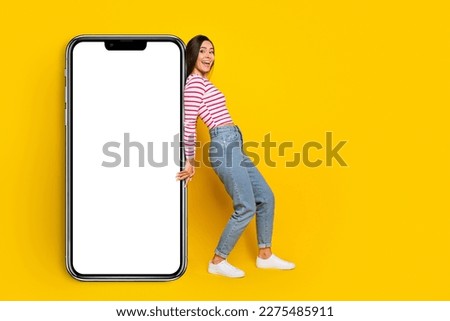 Photo of nice gorgeous adorable cheerful woman wear striped shirt jeans hold banner empty space isolated on yellow color background